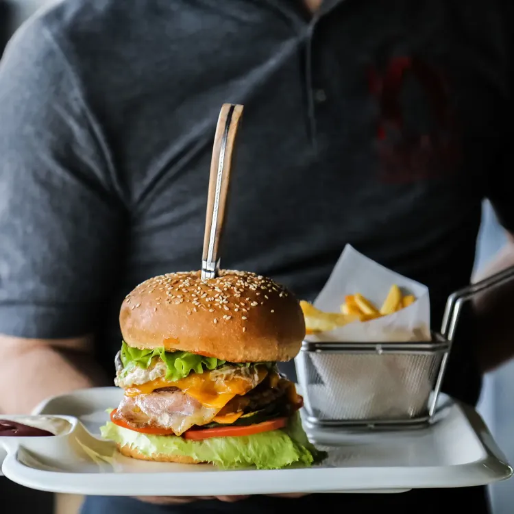 man-holding-plate-with-beef-burger-lettuce-cheese-tomato-cucumber-egg-french-fries-sauce-side-view.jpg